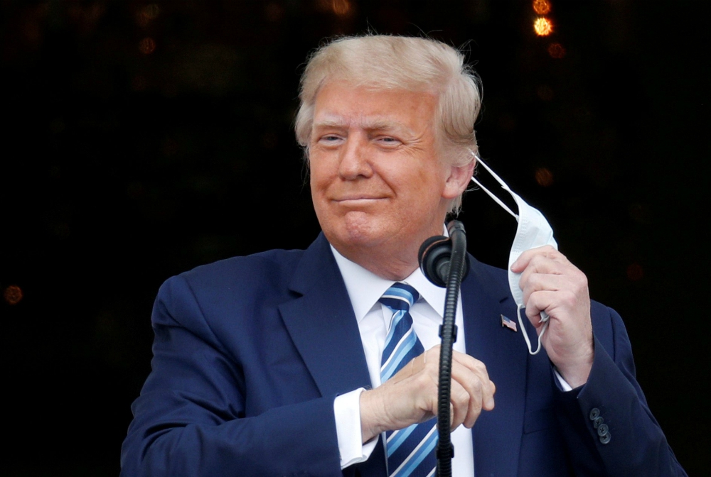 President Donald Trump takes off his face mask Oct. 10 as he comes out on a White House balcony in Washington to speak to supporters gathered for a rally on the South Lawn. (CNS/Reuters/Tom Brenner)