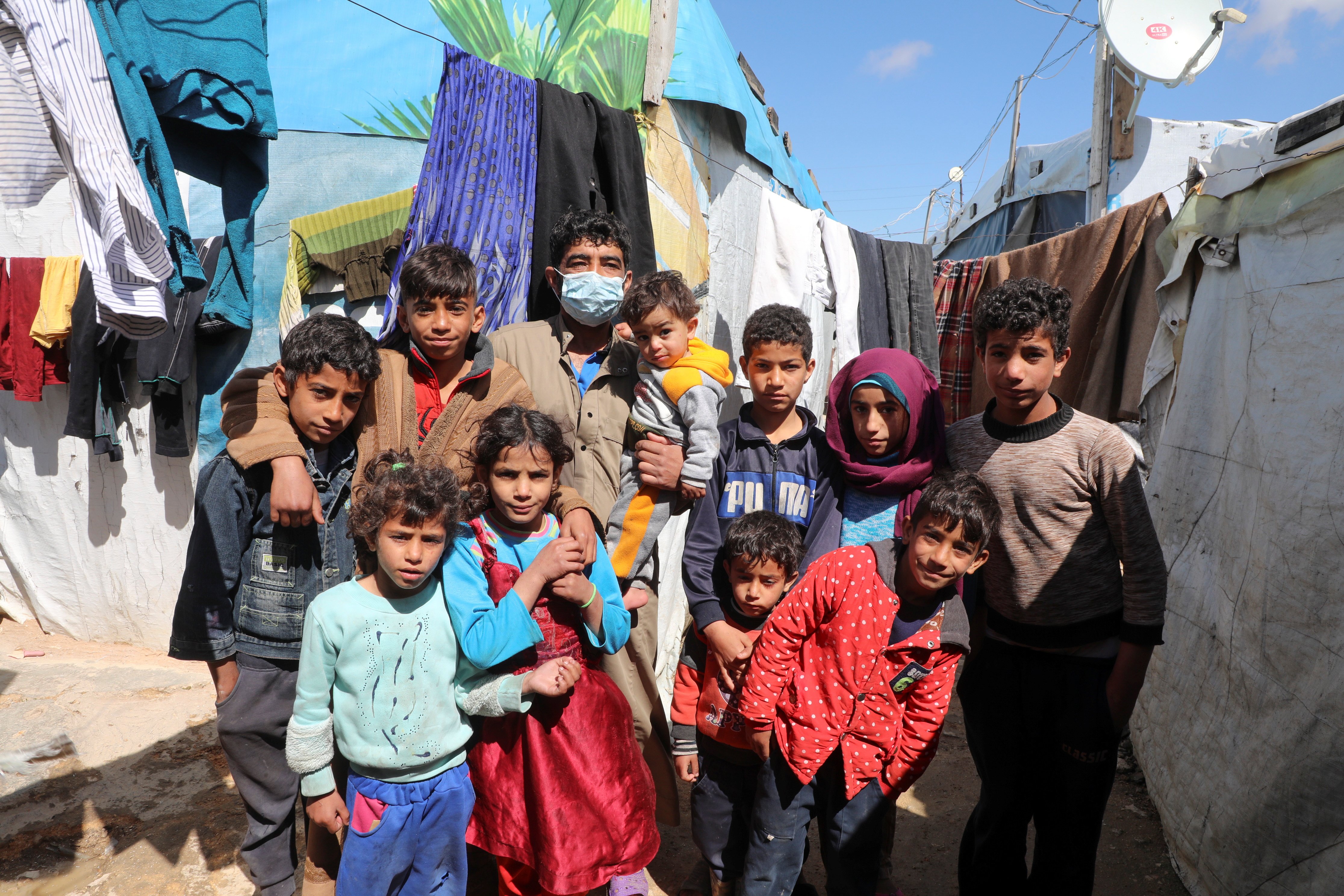 Syrian refugee Abd al-Razzak Dasher stands with his children at an informal tent settlement in the Bekaa Valley in Lebanon March 12, 2021. As Syria marks 10 years of devastating conflict, the country is in economic and social shambles with millions of peo