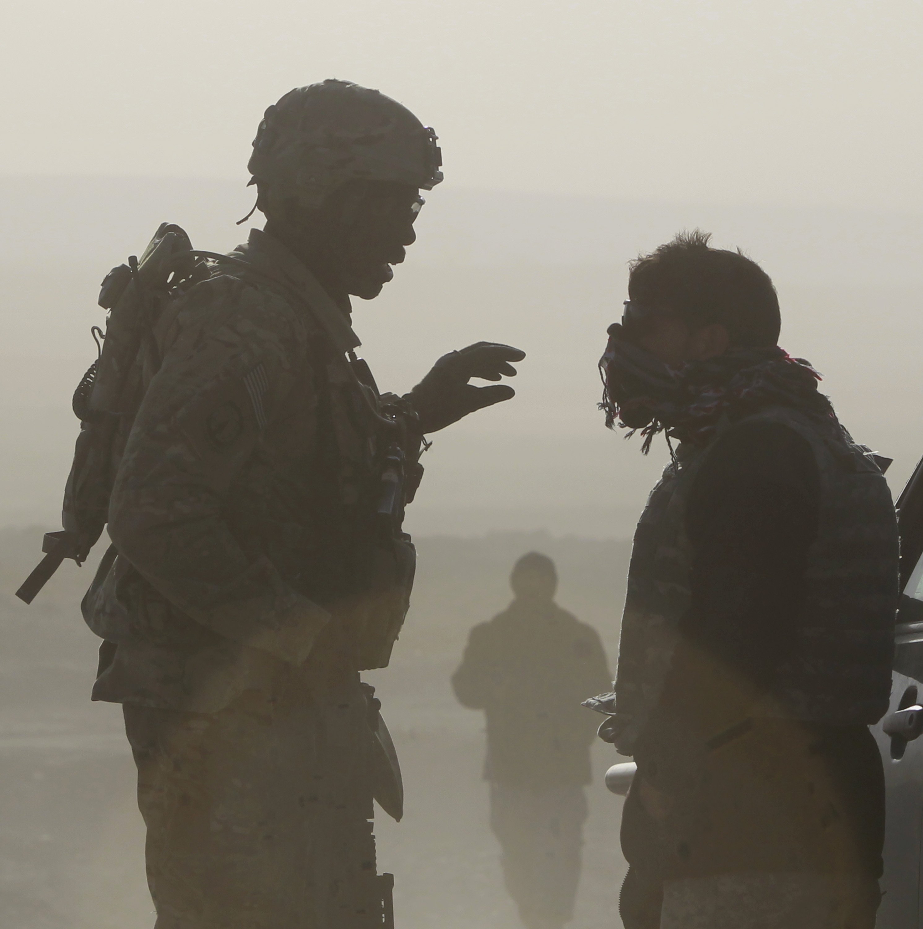 U.S. soldier Sgt. Michael Webb, left, from 549th MP Company Task Force Bronco and a translator are silhouetted as they talk to each other at a joint U.S. military and Afghan police checkpoint in Nangarhar province in eastern Afghanistan March 7, 2012. (CN