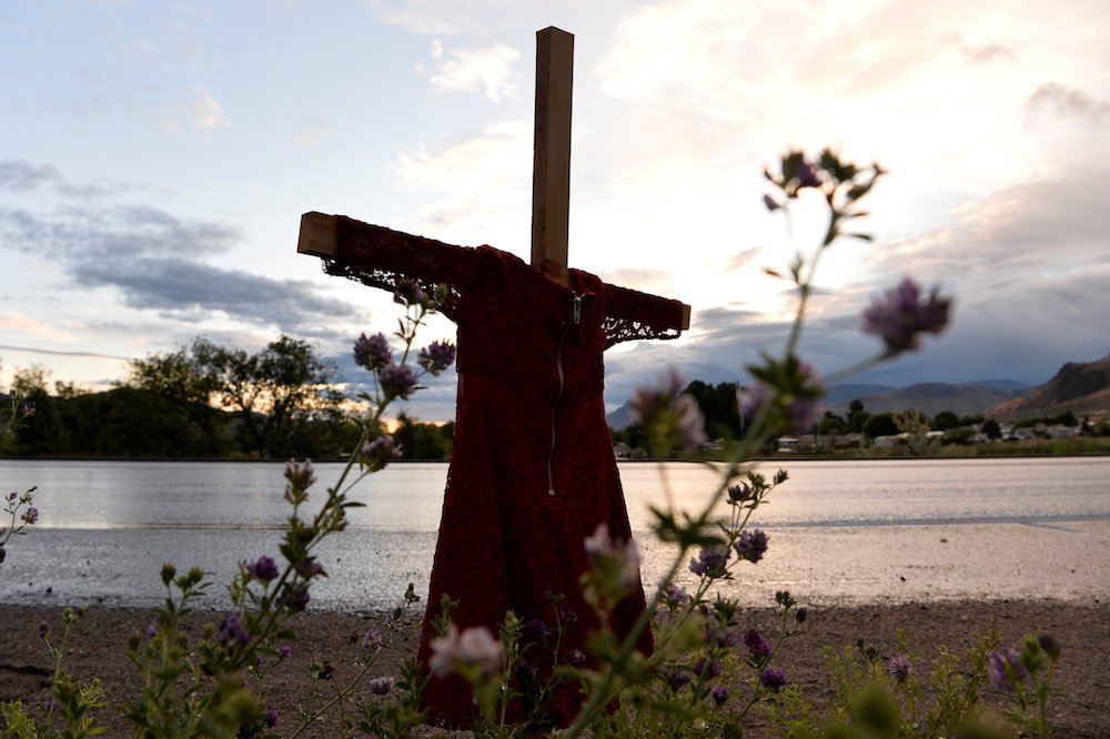 A child's red dress hangs on a stake near the grounds of the former Kamloops Indian Residential School in Kamloops, British Columbia. For years, Indigenous people in Canada have wanted an apology from the pope — on Canadian soil — for the church's role in