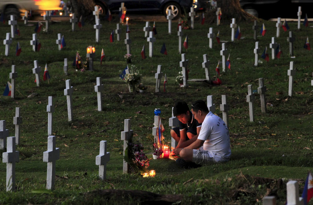 Filipinos light candles in front of the tomb of their deceased loved one, inside a military cemetery near Manila, Philippines, Oct. 31, 2015. Filipinos flock to cemeteries across the country to commemorate their departed loved ones for All Saints' Day and All Souls' Day. (CNS photo/Romeo Ranoco, Reuters)