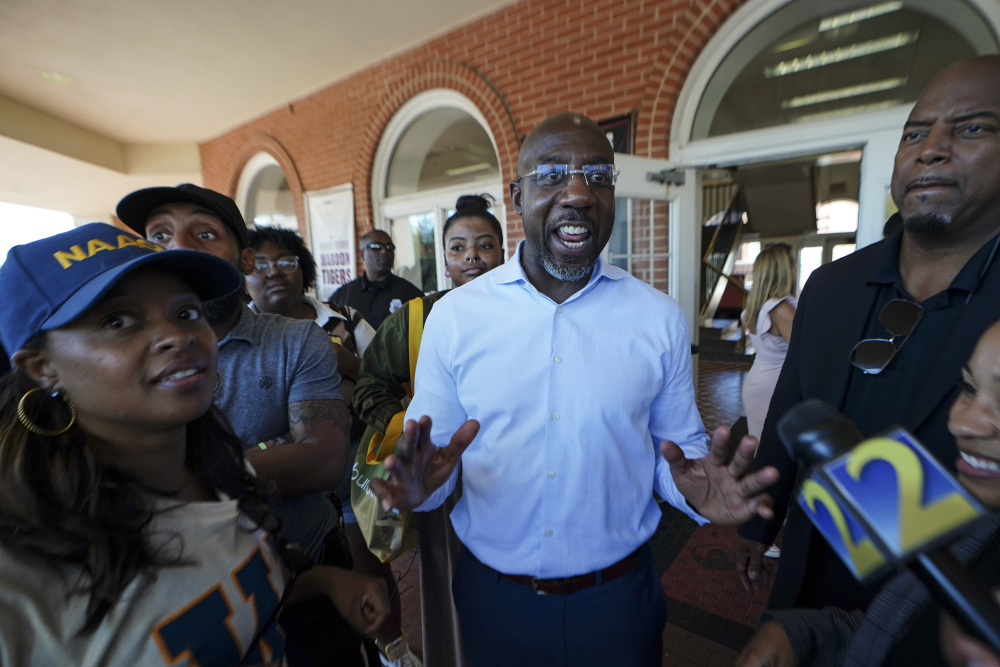 Democratic nominee for U.S Senate Sen. Raphael Warnock speaks to a reporter during a campaign stop on the campus of Morehouse College Tuesday, Nov. 8, 2022, in Atlanta. (AP Photo/John Bazemore)