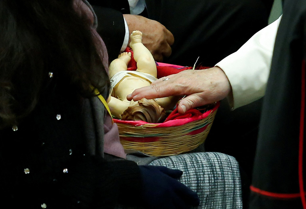 Pope Francis touches a figurine of the baby Jesus during an audience with the donors of the Vatican Christmas tree and the Nativity scenes, Dec. 3, 2022, in the Paul VI hall at the Vatican. (CNS/Reuters/Remo Casilli)