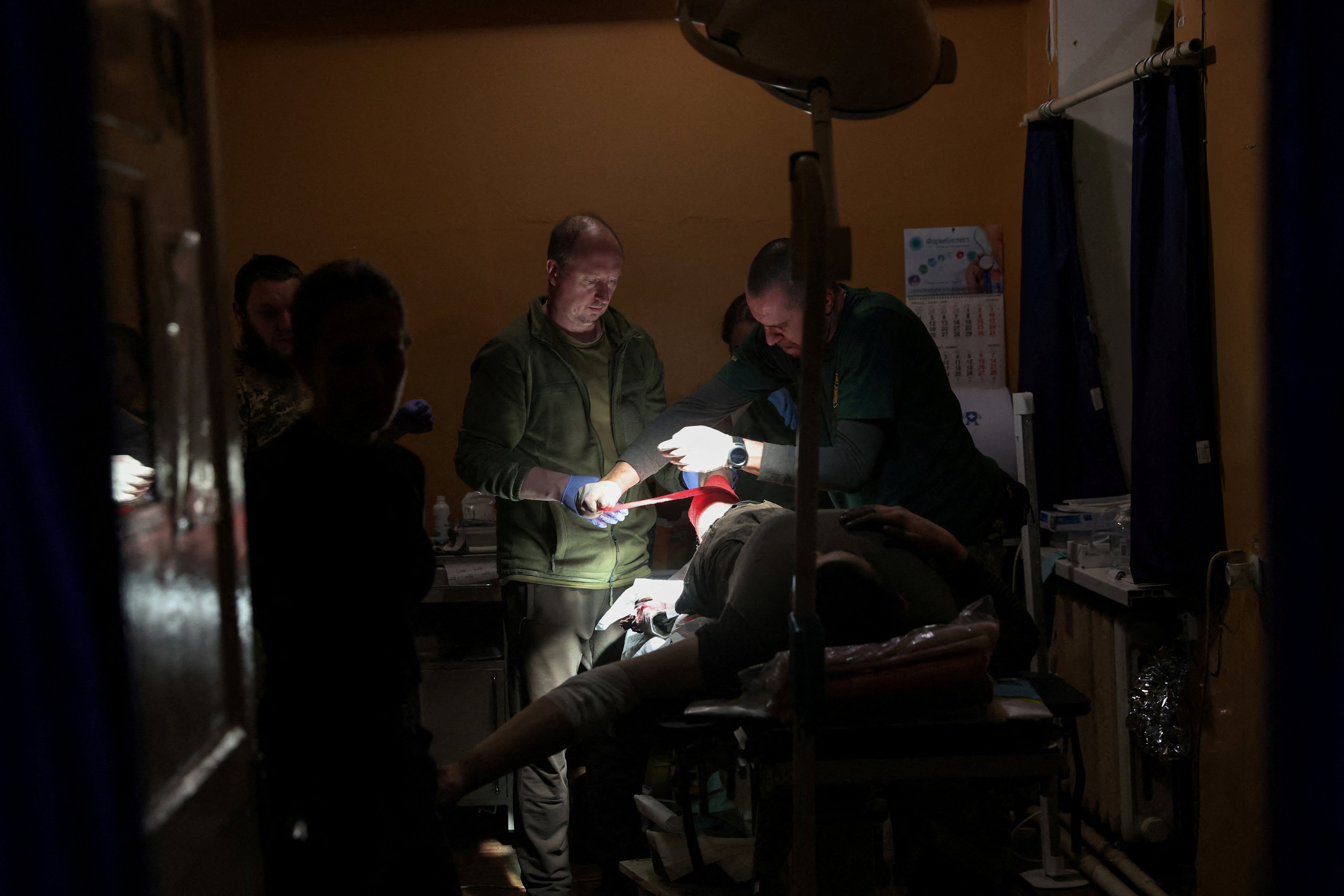 two men treat a patient in a dark room