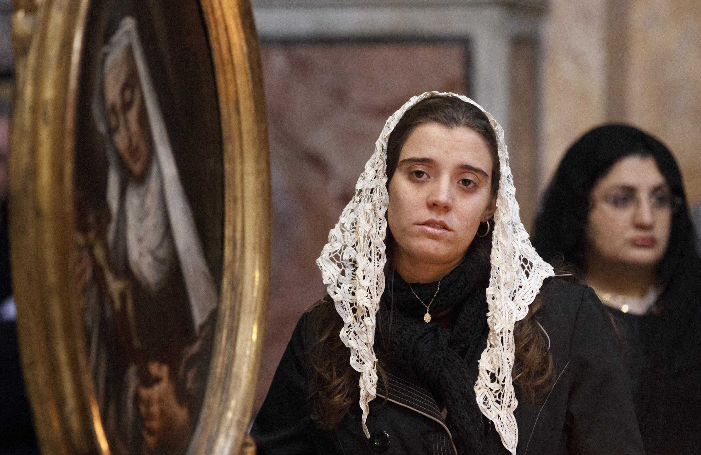 Maria Regina Zucchi of São Paulo stands near a painting of a saint at the Church of the Holy Trinity of the Pilgrims, a Fraternity of St. Peter parish, in Rome, Nov. 1, 2012. (CNS photo/Paul Haring)