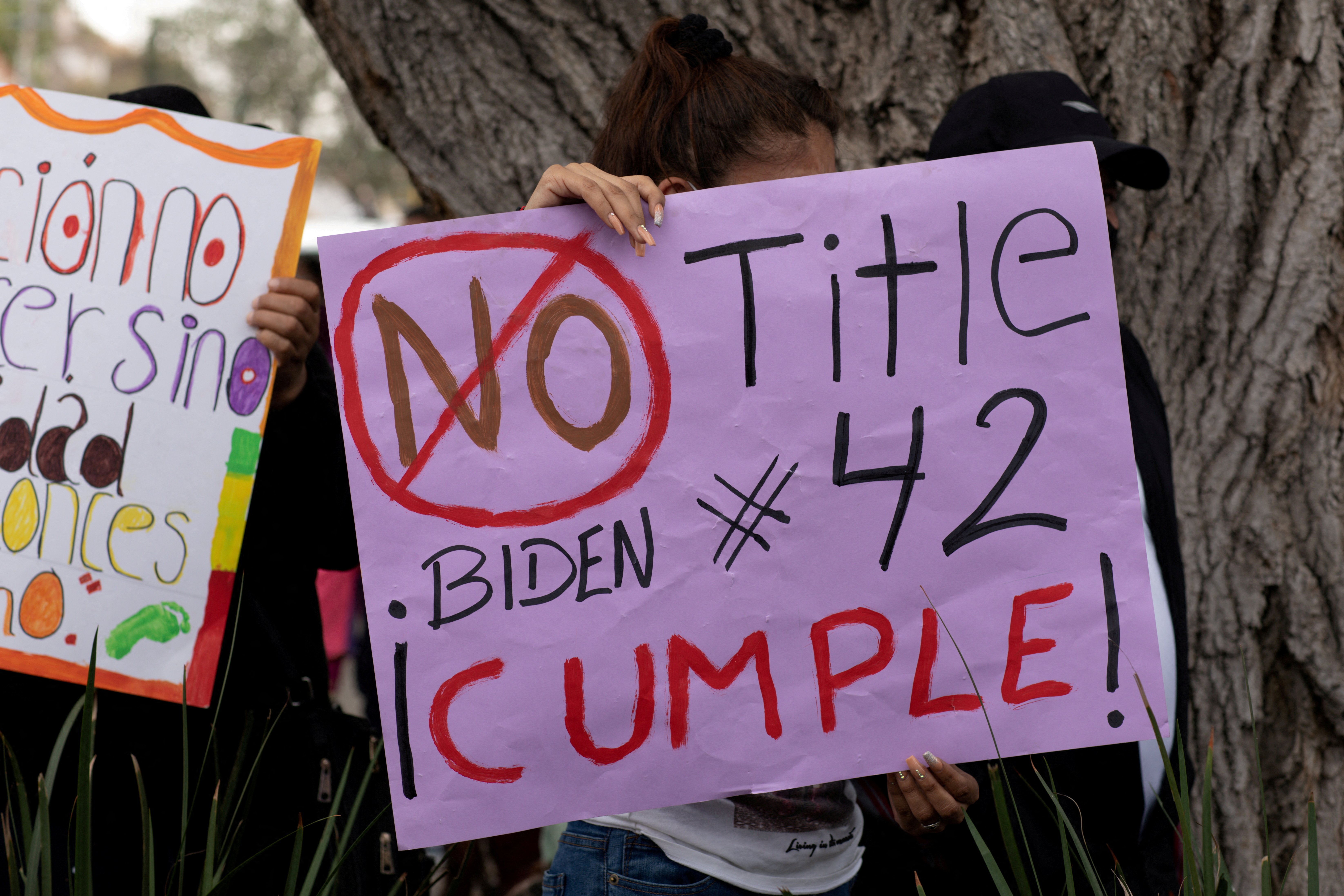 A woman in Nogales, Mexico, holds a sign Nov. 8, 2021, that reads, "No Title 42 Biden ¡Cumple!" at a migrant-led protest against enforcement of the U.S. health code's Title 42 provision, which is being used to keep many migrants out because of concerns ab