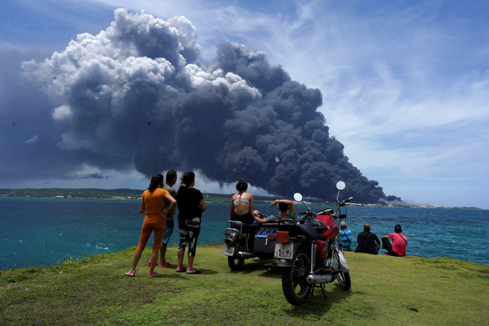 People watch as smoke billows over a large oil storage facility that exploded near Cuba's supertanker port in Matanzas Aug. 8, 2022. The deadly fire is threatening to plunge the island into a deeper energy crisis. (CNS photo/Alexandre Meneghini, Reuters)