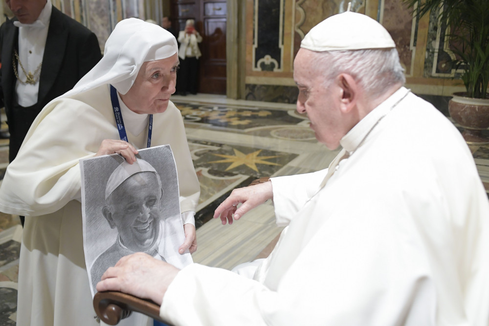 Pope Francis looks at artwork of himself presented by a nun during an audience with the participants of a symposium on "Holiness Today," sponsored by the Dicastery for the Causes of Saints, at the Vatican Oct. 6, 2022