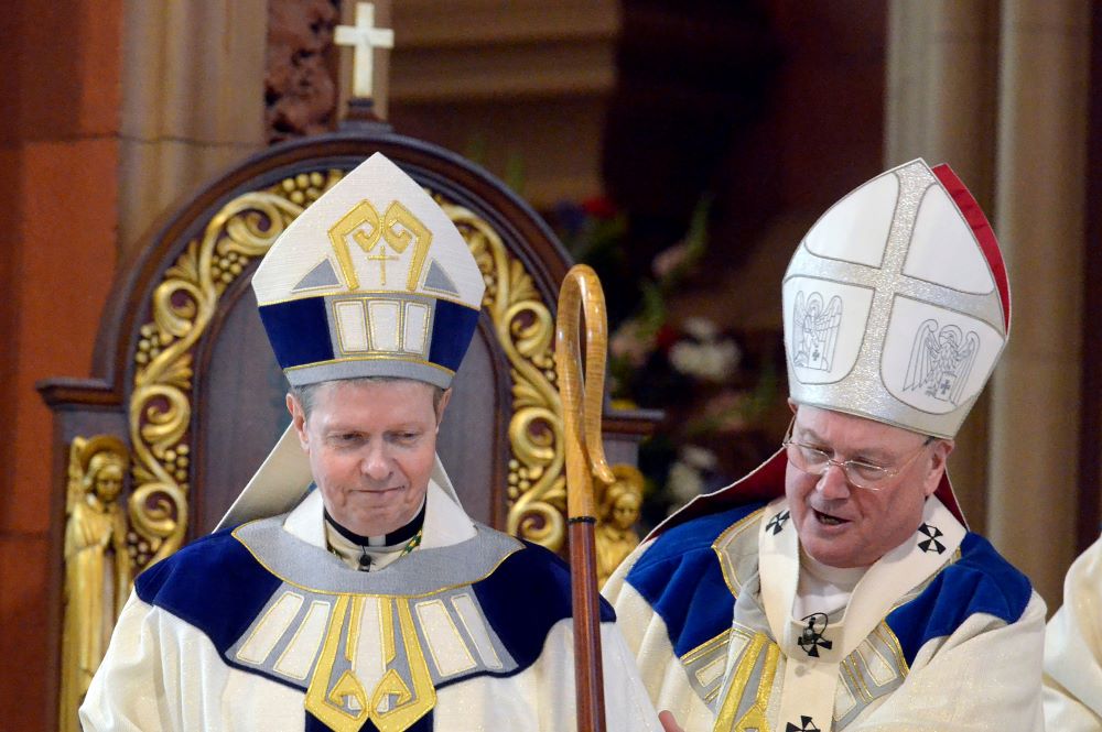 Newly ordained Bishop Edward B. Scharfenberger, left, is helped with his crosier by Cardinal Timothy Dolan, April 10, 2014, during his installation as 10th bishop of the Albany Diocese in New York. 