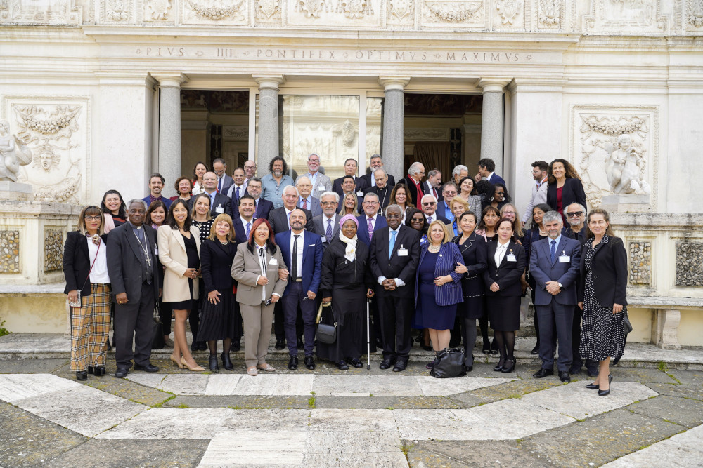 A medium-sized group of people poses for a group photo in front of a marble wall