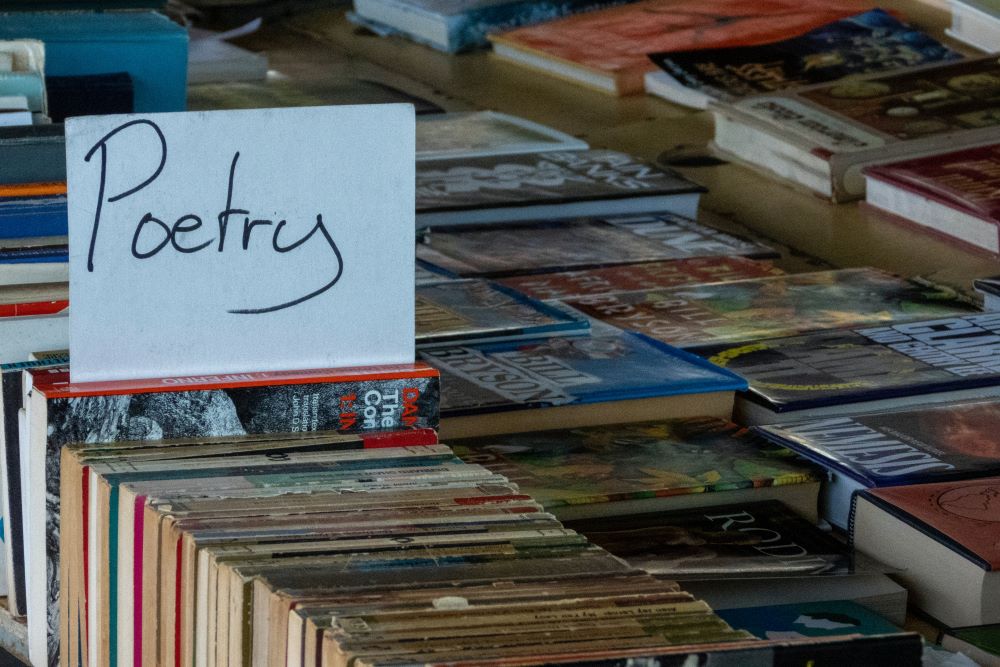 Handwritten sign labeled "Poetry" marks a spot in a bin of books.