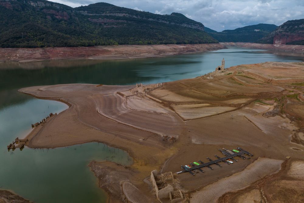 Dry, cracked land is visible around at the Sau reservoir, about 100 km (62 miles) north of Barcelona, Spain, Tuesday, April 18, 2023. (AP Photo/Emilio Morenatti)