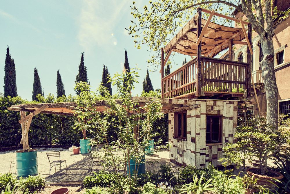 At the courtyard of the "Social Friendship: Meeting in the Garden" exhibition at the Venice Biennale of Architecture, roosters crow, cats roam freely among the grounds' more than 100 plants, and neighboring young people stop by to rest or read on a garden bench or to help collect the urban vegetable harvest. (Courtesy of the Vatican's Dicastery for Culture and Education)