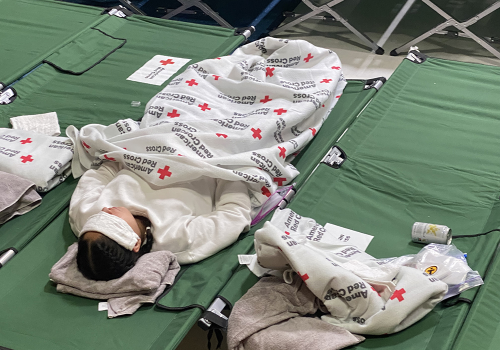 A woman rests on a cot May 13 at a temporary shelter the Diocese of El Paso set up at Our Lady of Assumption Parish in El Paso, Texas. Many migrants arrived at the shelter thirsty, tired and hungry after days or weeks of travel toward the U.S.-Mexico border. (NCR photo/Rhina Guidos)