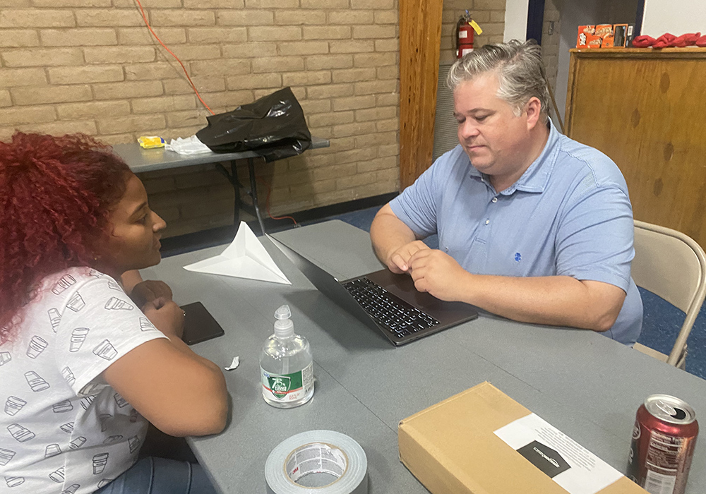 Dylan Corbett, executive director of Hope Border Institute, which works closely with the Diocese of El Paso on immigration matters, talks to a migrant at a temporary shelter the Diocese of El Paso set up at Our Lady of Assumption Parish in El Paso, Texas. There is uncertainty about what will happen given new immigration policies affecting migrants, Corbett said. (NCR photo/Rhina Guidos)