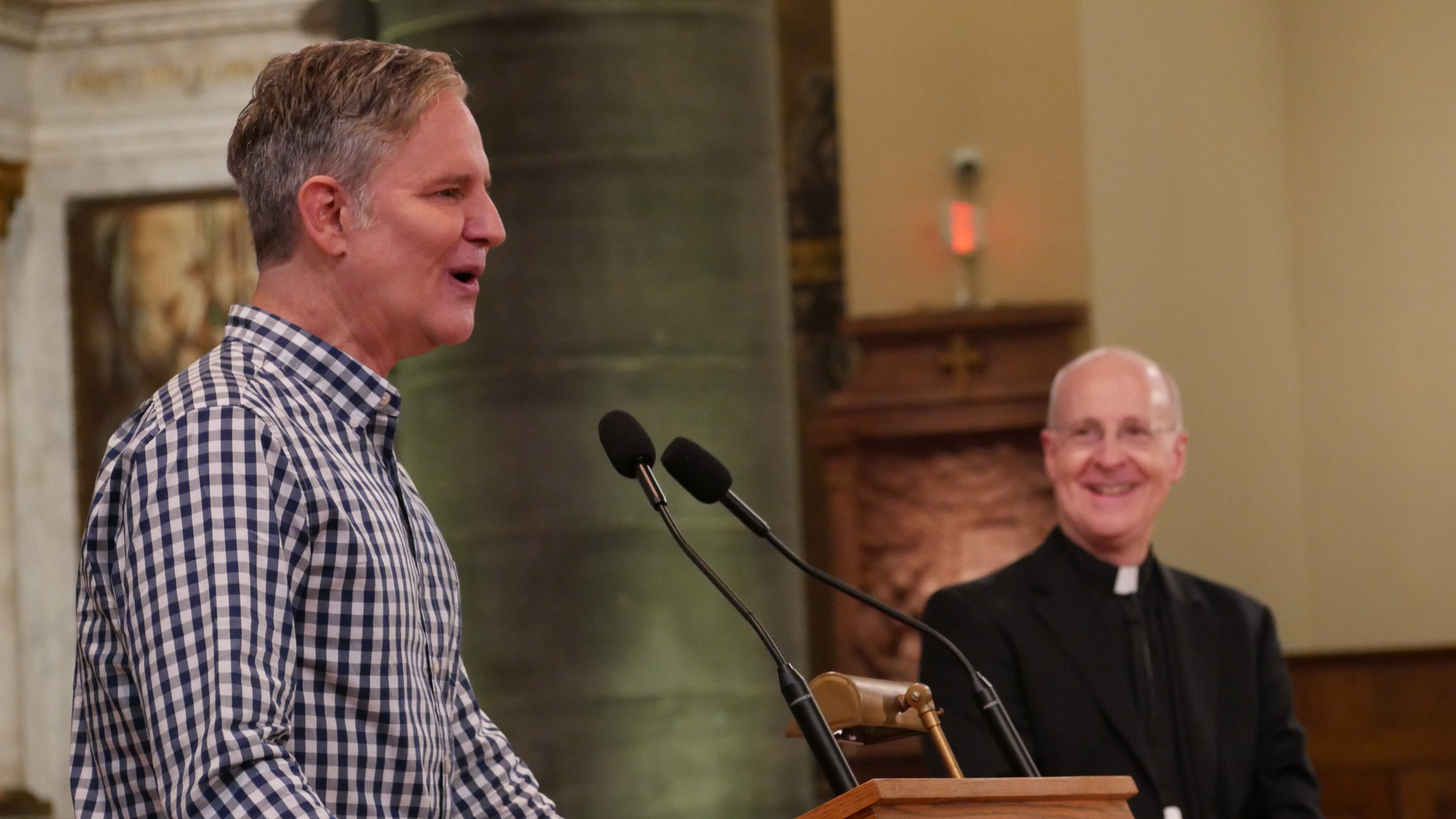 Juan Carlos Cruz, a member of the Pontifical Commission for the Protection of Minors, speaks to the Outreach conference June 18 as Jesuit Fr. James Martin looks on. (Courtesy of America Media/Cristobal Spielmann)