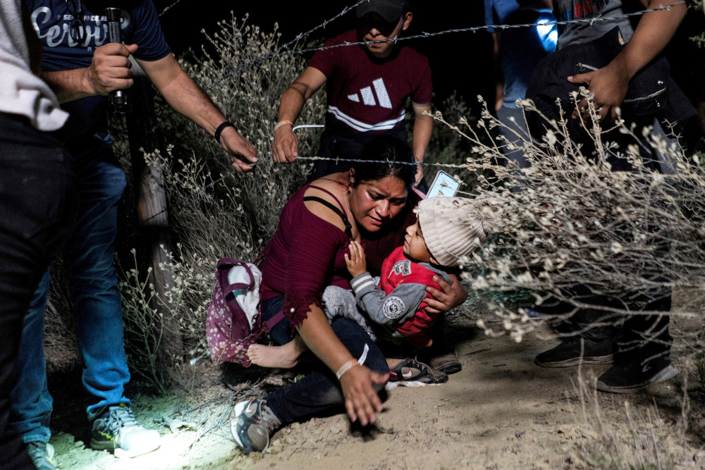 Asylum-seeking migrants' families go under a barbed wire fence while being escorted by a local church group to the location where they turn themselves in to the U.S. Border Patrol, after crossing the Rio Grande river into the United States from Mexico, in Roma, Texas, April 16, 2021. (OSV News photo/Go Nakamura, Reuters)