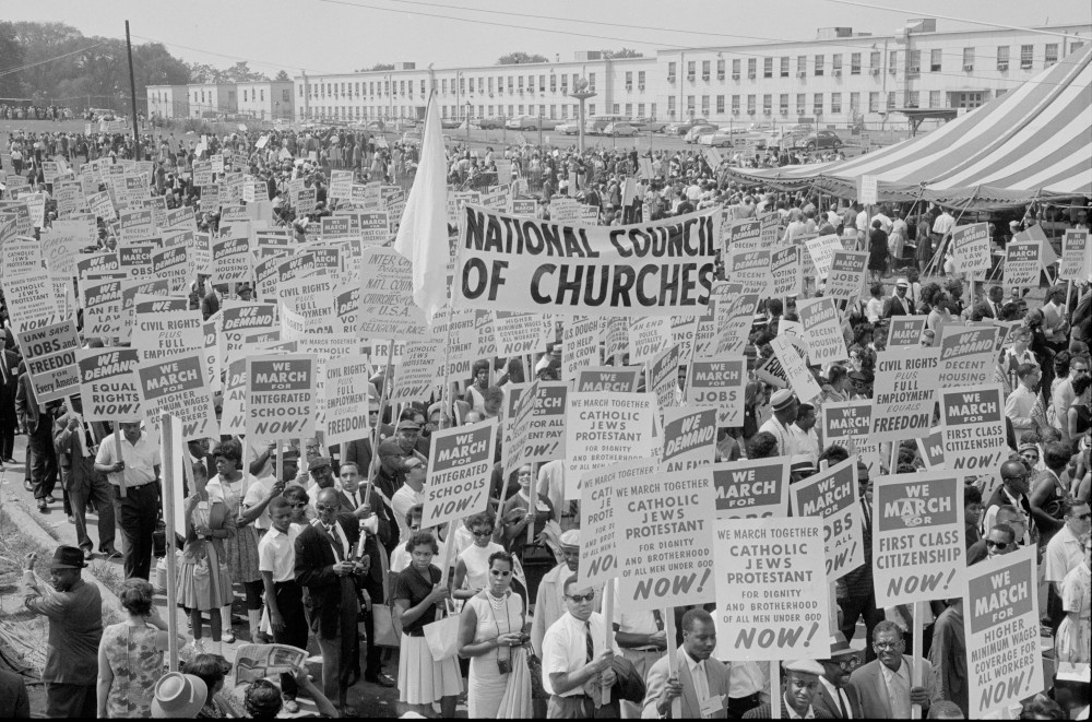 A black and white photo of protesters on the National Mall carrying signs for racial justice