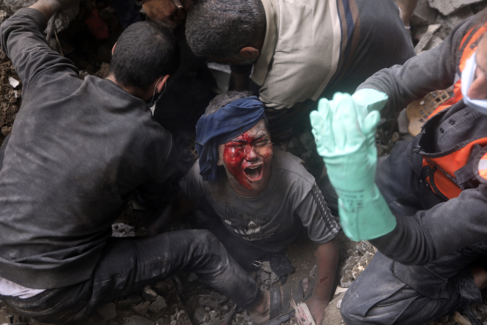 An injured Palestinian boy cries as rescuers try to pull him out of the rubble of a destroyed building after an Israeli airstrike in Bureij refugee camp, Gaza Strip, Nov. 2. (AP/Mohammed Dahman)