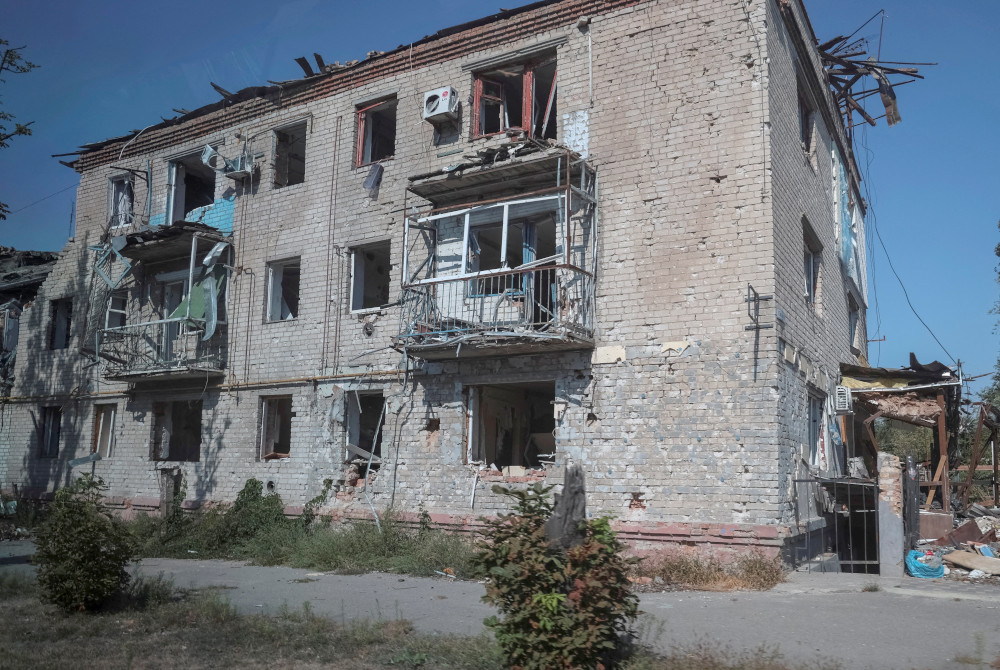 A three-story building is visible without windows and a clearly damaged roof and balconies