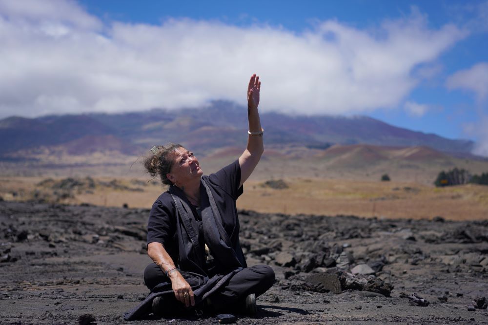 Kealoha Pisciotta, a cultural practitioner and longtime activist, sits on lava rock part of the way up Mauna Kea while giving an interview on the Big Island of Hawaii, on Saturday, July 15, 2023. Over the last 50 years, astronomers have mounted 13 giant astronomical observatories on Mauna Kea's summit. In 2019, Native Hawaiians including Piscioitta staged a year-long protest over construction of an additional telescope. (AP/Jessie Wardarski)