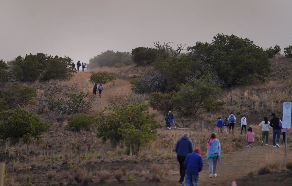 Visitors walk to an observation point near the Mauna Kea visitors center at 9,000 feet in Mauna Kea, Hawaii on Saturday July, 15, 2023. (AP Photo/Jessie Wardarski)