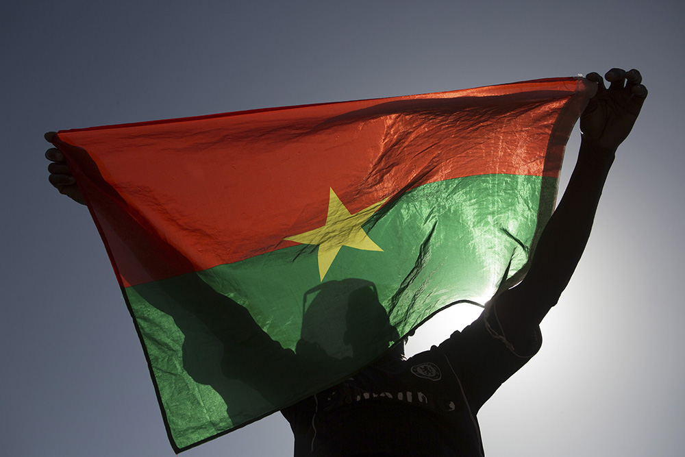 A protester holds up a Burkina Faso flag in Ouagadougou, the capital of Burkina Faso, in 2014. At least 15 people were killed in an attack by gunmen on Catholics gathered for Sunday Mass in a Burkina Faso village Feb. 25, 2024. (OSV News/Reuters/Joe Penney)