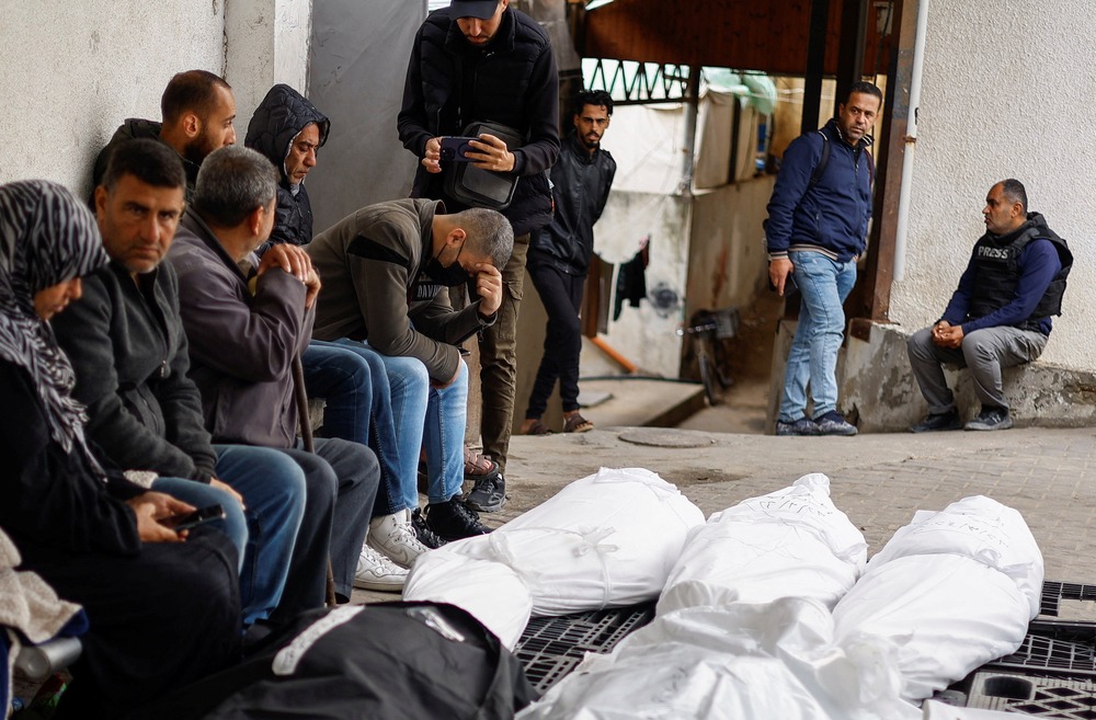 Palestinian mourn with shrouded bodies in foreground.