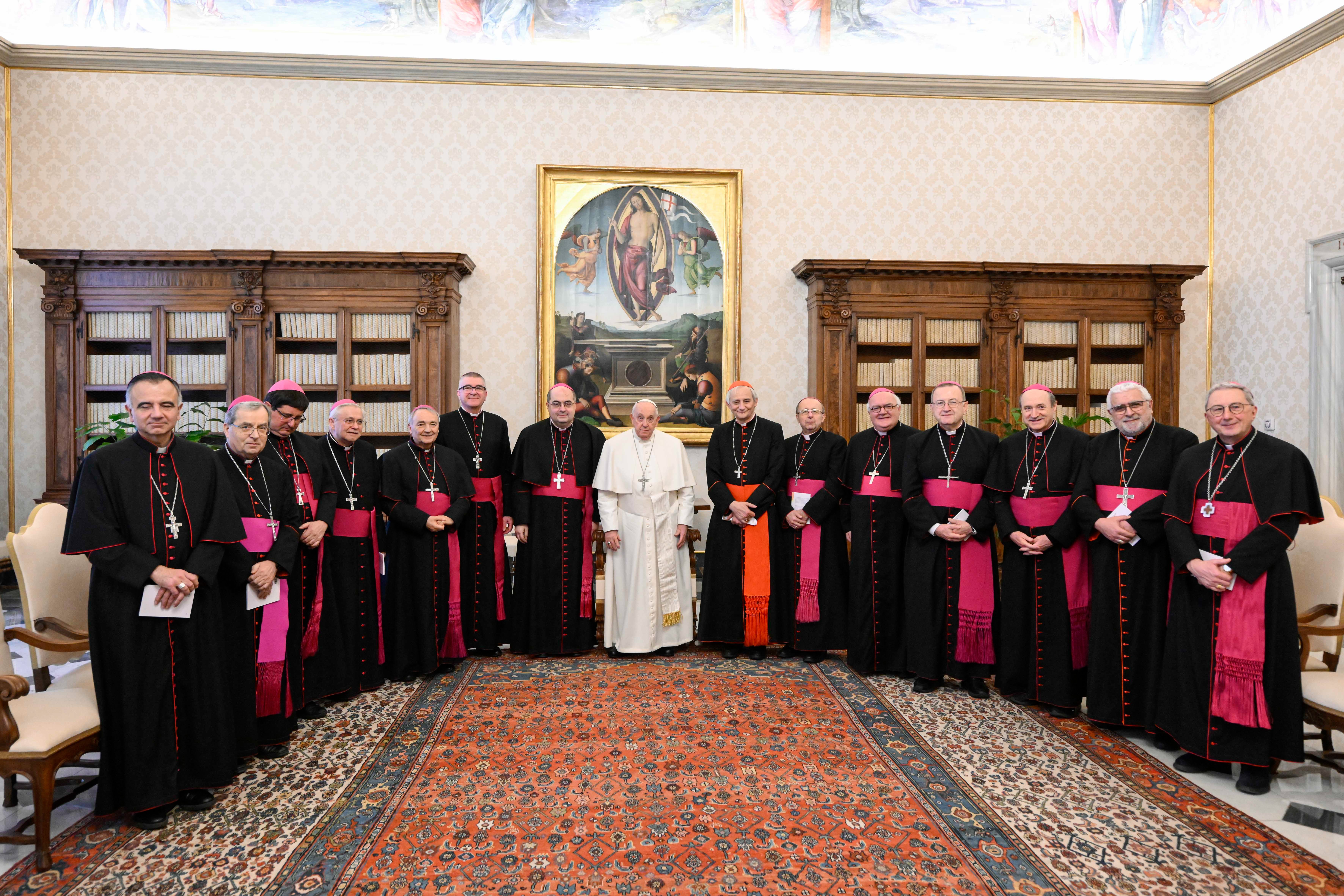 Bishops line up around Pope Francis in apostolic library. 