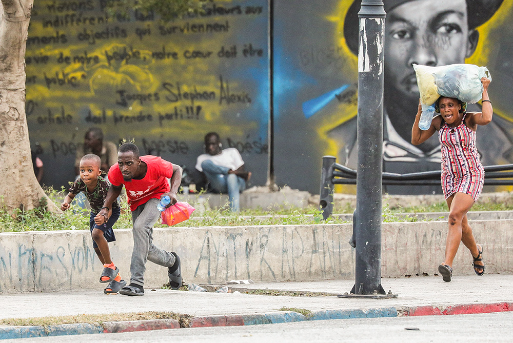 People take cover from gunfire near the National Palace in Port-au-Prince, Haiti, March 21. (OSV News/Reuters/Ralph Tedy Erol)