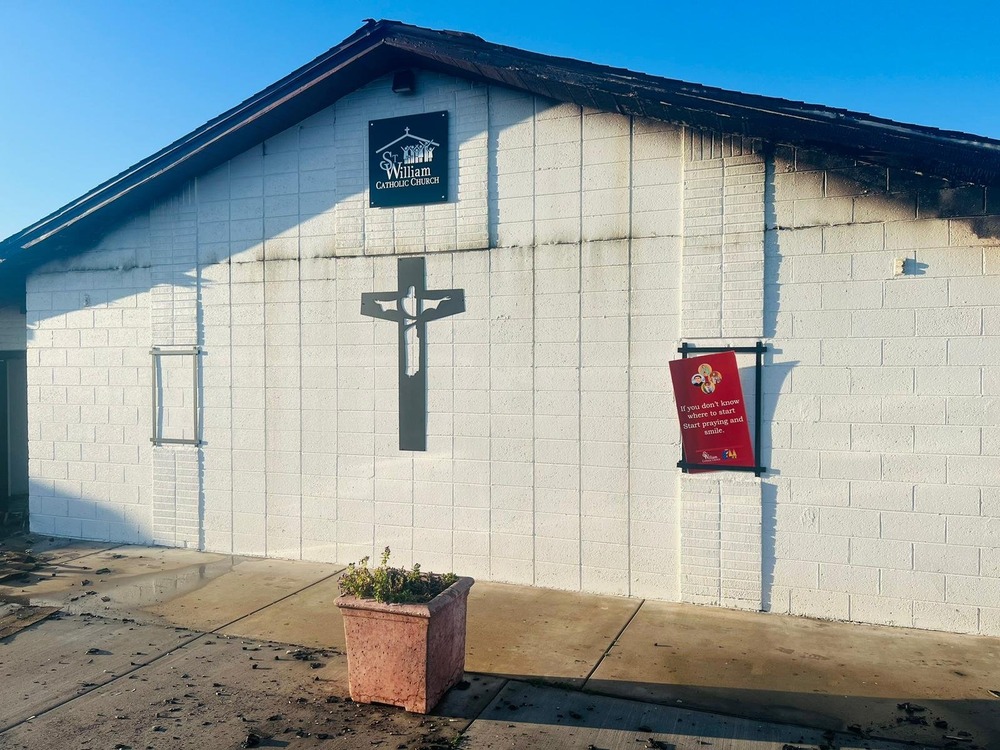 Front of small, one-story church building pictured with fire damage near blackened roof