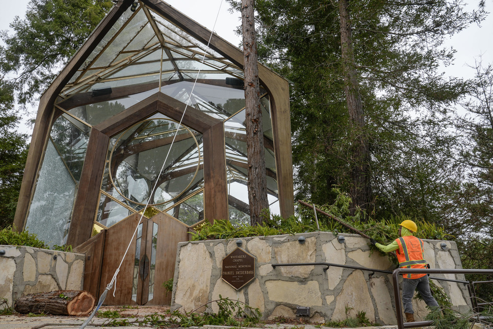 Chapel seen amidst trees, maintenance worker seen in bottom right corner. 