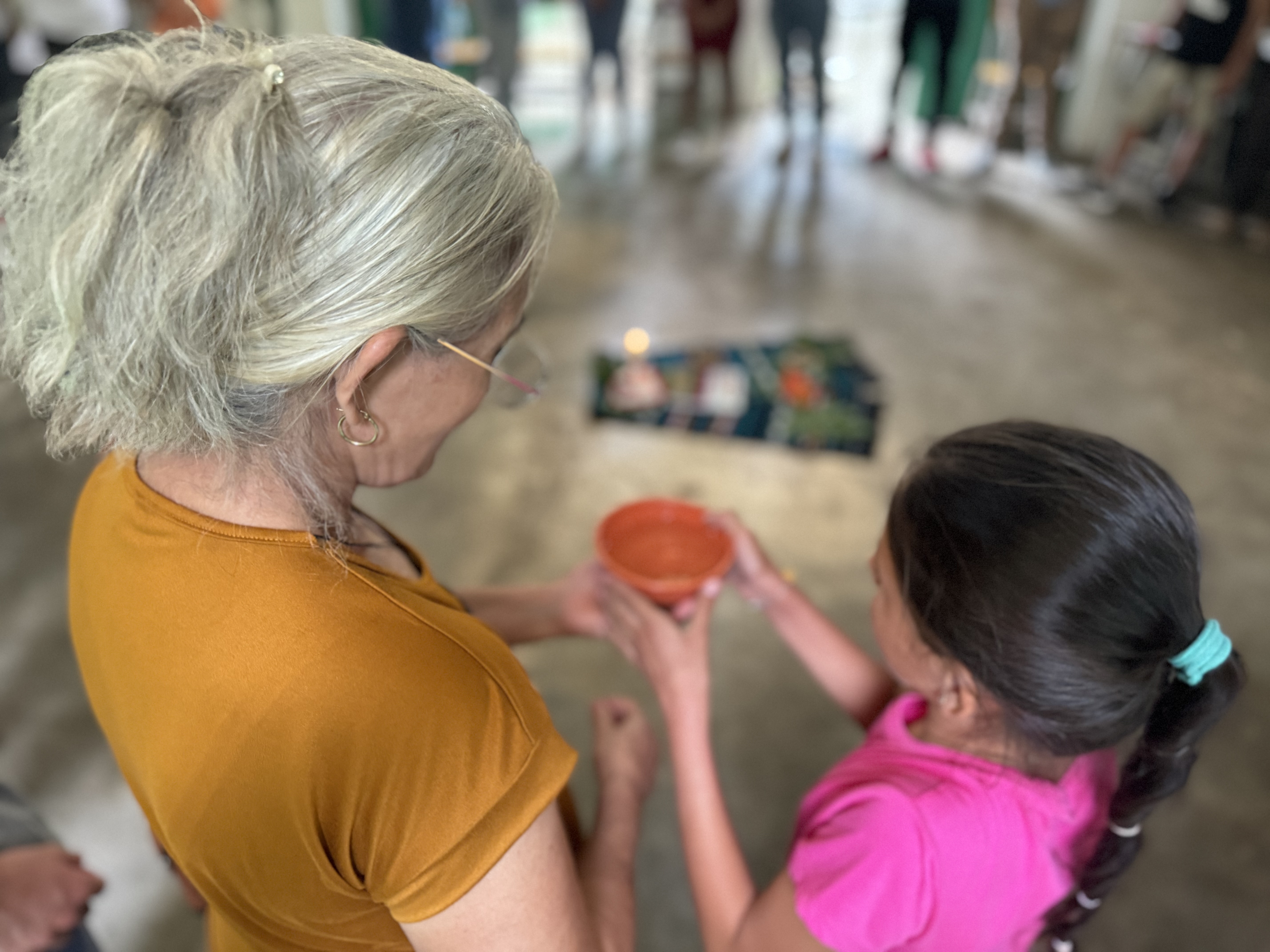 A survivor of a massacre shares water from the Sumpul River with a girl during an intergenerational activity on April 27 in Arcatao, El Salvador, commemorating the killing of more than 600 people in May 1980. (GSR photo/Rhina Guidos)