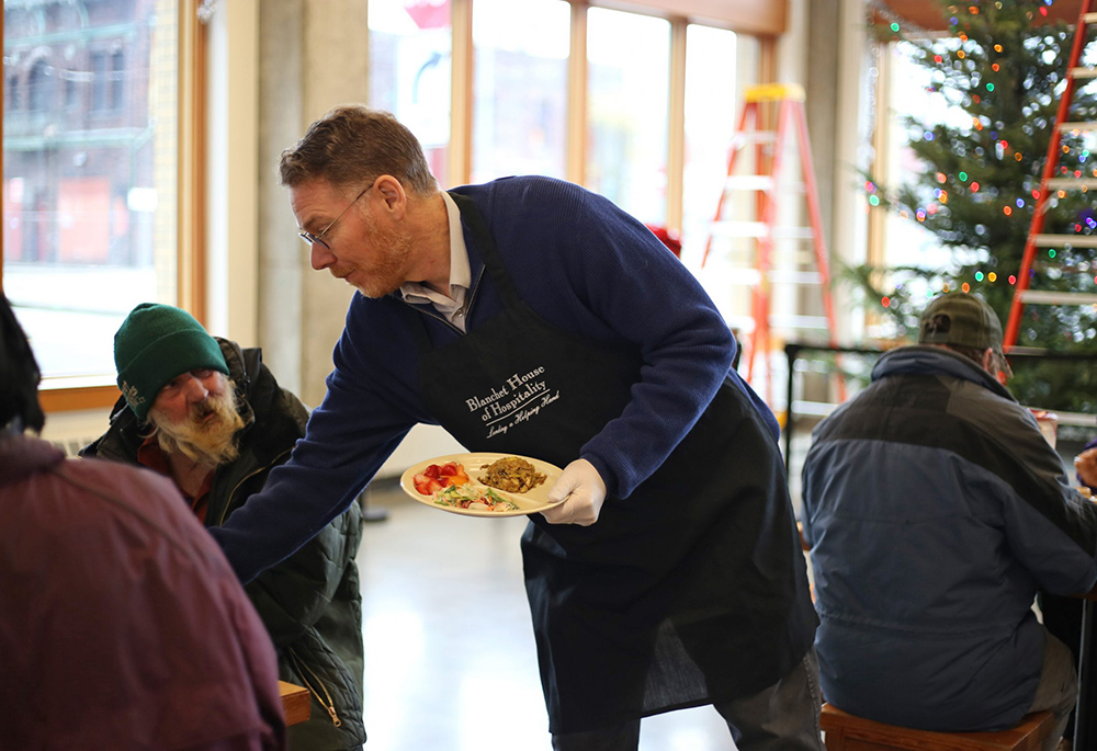 Scott Kerman, executive director of Blanchet House in downtown Portland, serves a meal to a guest near Christmas in 2019. Kerman worries how camping bans will impact the many disabled people living on the streets. (Courtesy of Blanchet House)