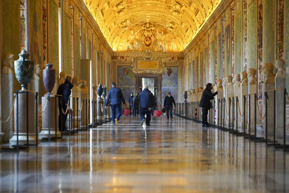 Individual walk down long, ornate passageway. 