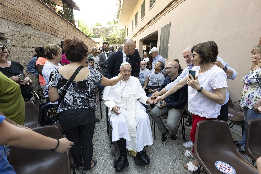 Pope Francis, in a wheelchair, is caressed by devotees. 