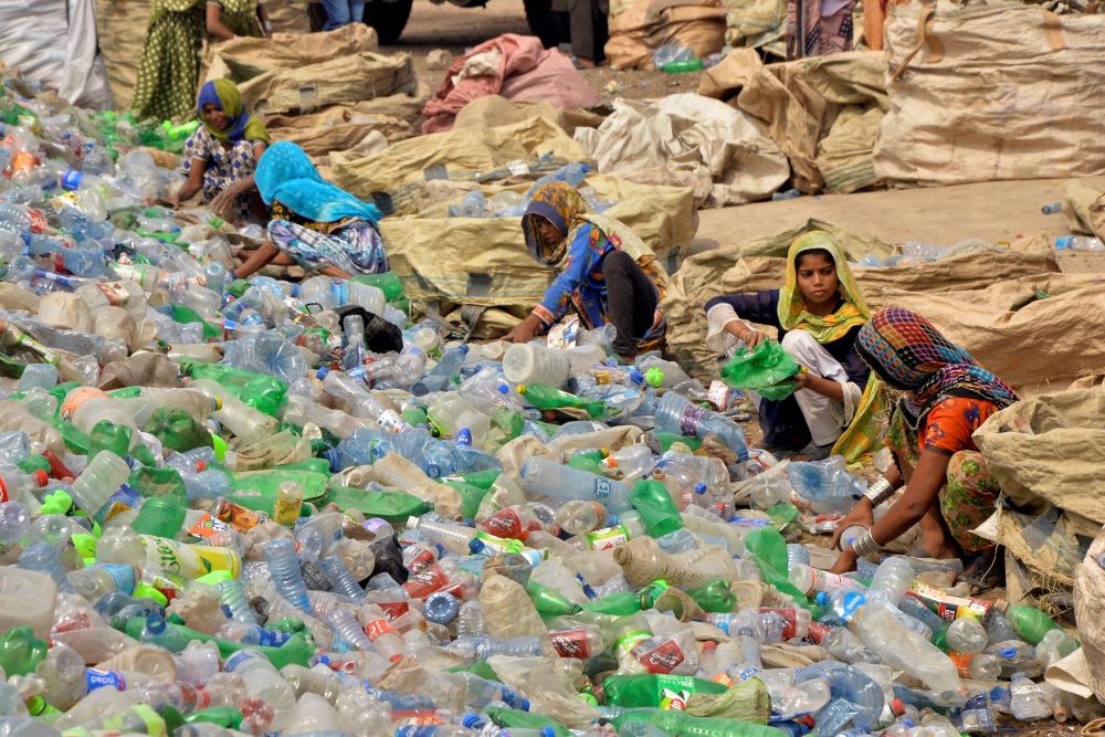 Pakistani laborers, mostly women, sort through empty bottles at a plastic recycling factory in Hyderabad, Pakistan, April 30, 2023.
