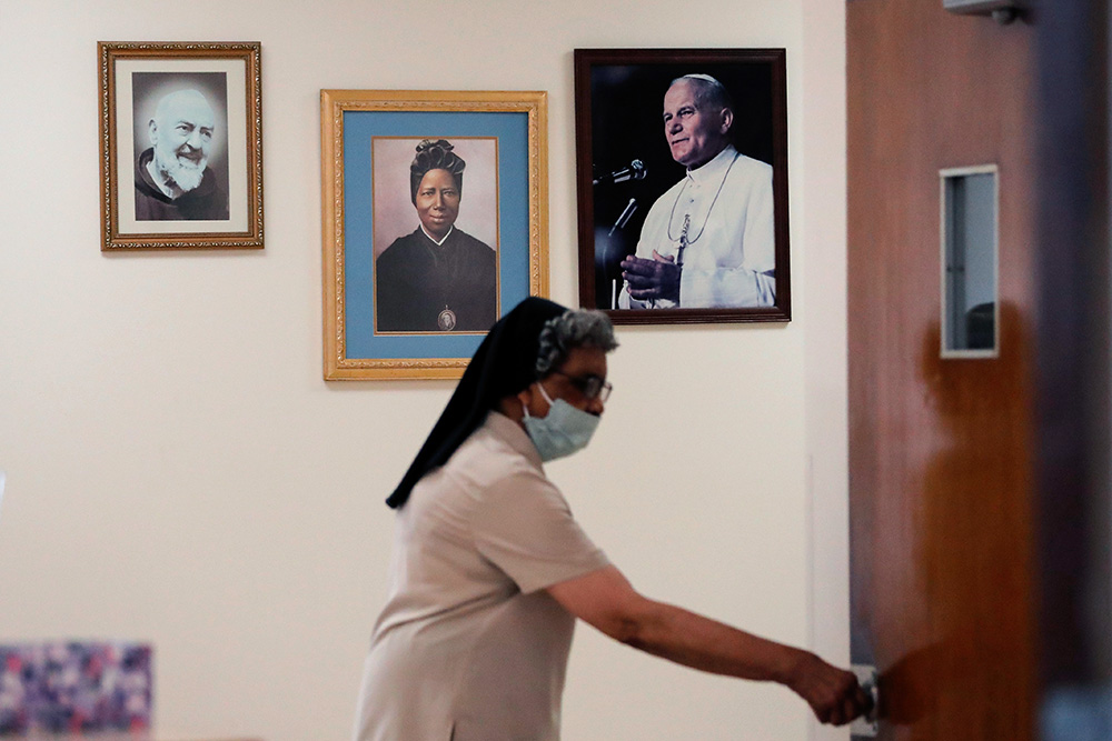 Holy Family Sr. Laurita Oliver walks past portraits of St. Pio of Pietrelcina, human trafficking survivor St. Josephine Bakhita of Sudan, and St. Pope John Paul II during a retreat at the Sisters of the Holy Family Motherhouse in New Orleans in 2020. (AP/Gerald Herbert)