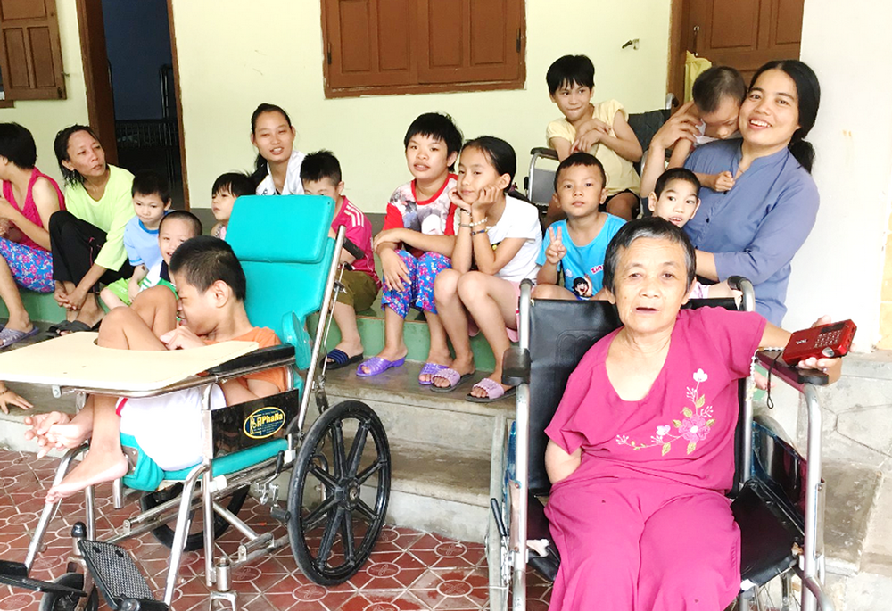 Sr. Mary Madeleine Trinh Thi Huong (right), orphans, pregnant women and older adults pose for a group photo at her convent May 13, 2023, in Quang Tri province. (Joachim Pham)