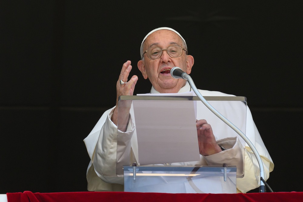 Pope Francis speaks from lectern, right hand raised in expression