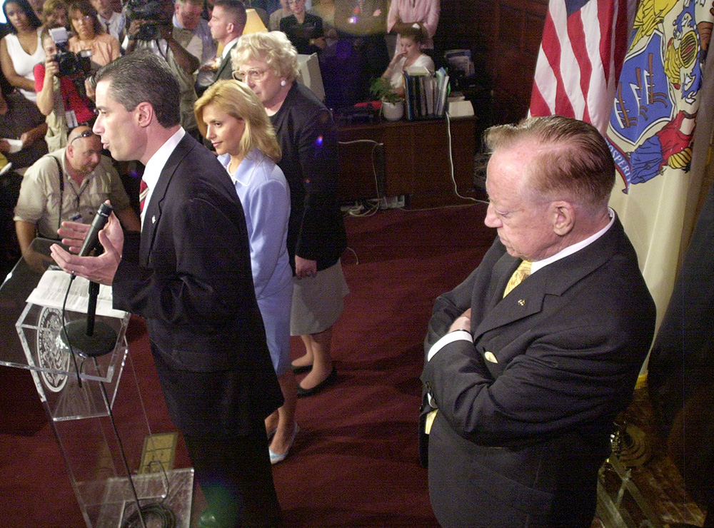 Jim McGreevey announces his resignation as governor of New Jersey at a packed news conference, with his wife, Dina Matos, and his mother, Veronica McGreevey, at his side, and his father, Jack McGreevey, behind him, at the Statehouse in Trenton, New Jersey, Aug. 12, 2004. (AP/Daniel Hulshizer)