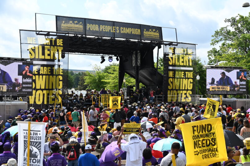 Large assemble holding sign, and a large platform bearing banners that read "the silent swing vote". 