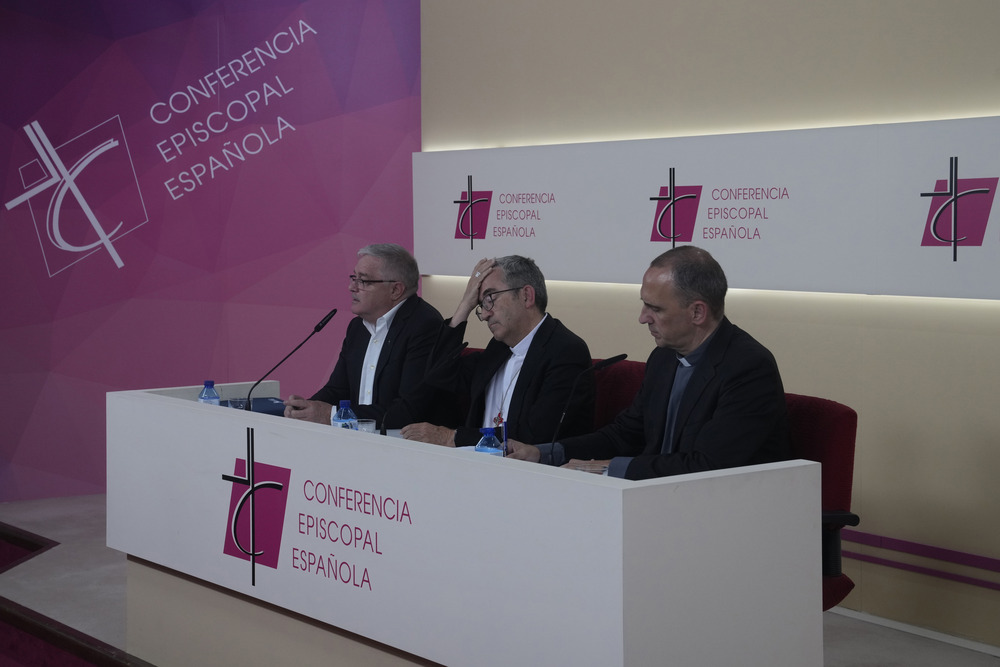 Officials sit at panel desk during press conference. 