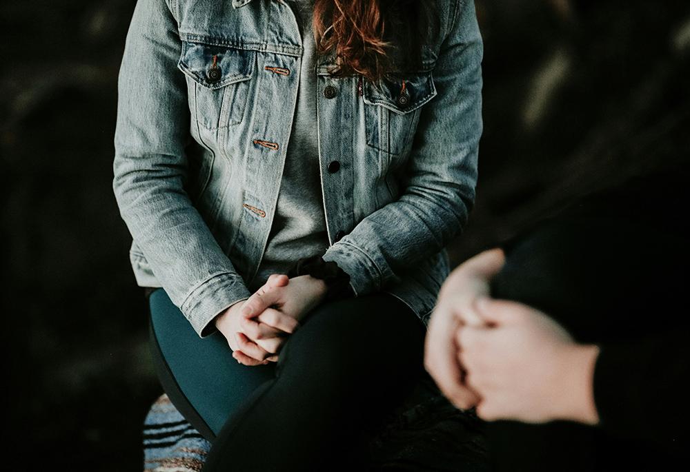 Two people sit with hands folded. (Unsplash/Priscilla Du Preez)