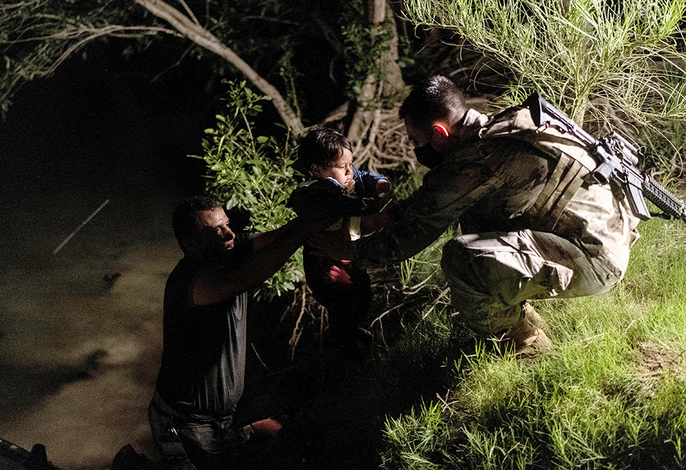 A human trafficker passes an asylum-seeking migrant child to a member of the U.S. National Guard in Roma, Texas, after crossing the Rio Grande into the United States from Mexico, on June 10, 2021. At a briefing at the Capitol June 6, 2024, representatives from the Alliance to End Human Trafficking and the National Advocacy Center of the Sisters of the Good Shepherd urged passage of three measures they said would aid efforts to combat the practice. (OSV News/Reuters/Go Nakamura)