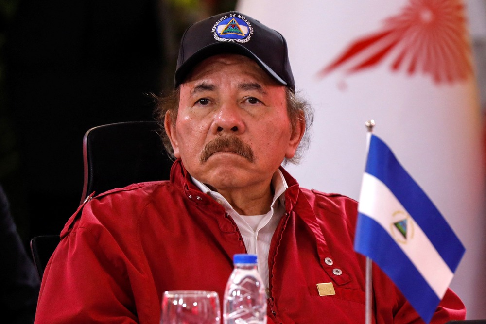 Ortega, seated, wears windbreaker and ball cap. 