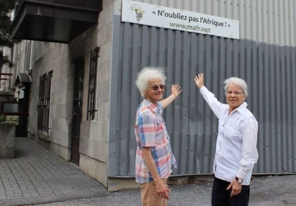 Srs. Rita Toutant, left, and Monique Bonnefoy point to a sign that reads "Do not forget Africa." 