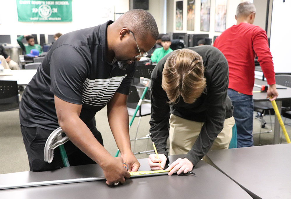 Kelly Stokes, instructor with Electricians Local 1 in St. Louis measures material with Michael Gallaway, on right, a student at St. Mary's South Side Catholic High School in the pre-apprenticeship program at the St Louis school. (Courtesy of St. Mary's South Side Catholic High School)