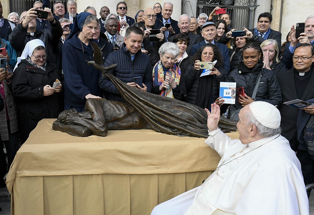 ope Francis waves to members of the Vincentian religious orders and lay communities Nov. 9, 2022, after blessing Canadian artist Timothy Schmalz' sculpture "Sheltering." The statue, which features a dove laying a blanket over a homeless person, was to be used in conjunction with a Vincentian project to build homes for some 10,000 people in 160 countries. (CNS/Vatican Media)