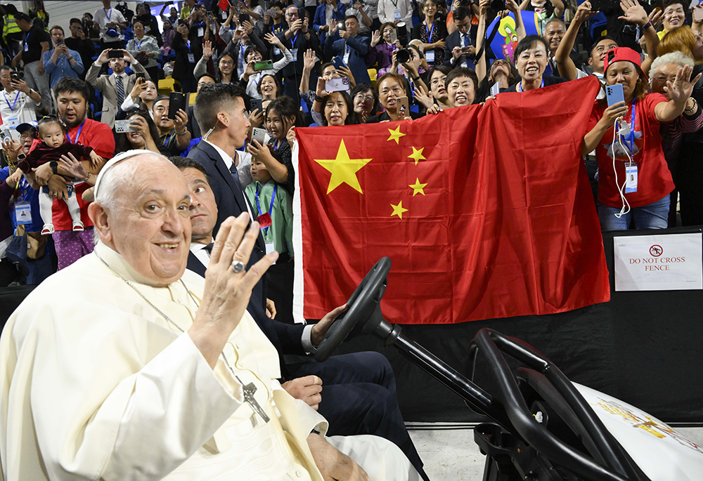 Pope Francis waves as people behind him raise a Chinese flag before the pope's Mass in Steppe Arena in Ulaanbaatar, Mongolia, Sept. 3, 2023. At the end of the Mass, the pope sent greetings to China and to Chinese Catholics. (CNS/Vatican Media)